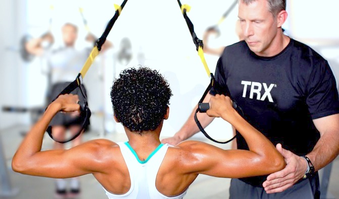 Personal trainers helps to workout with TRX Suspension Trainer