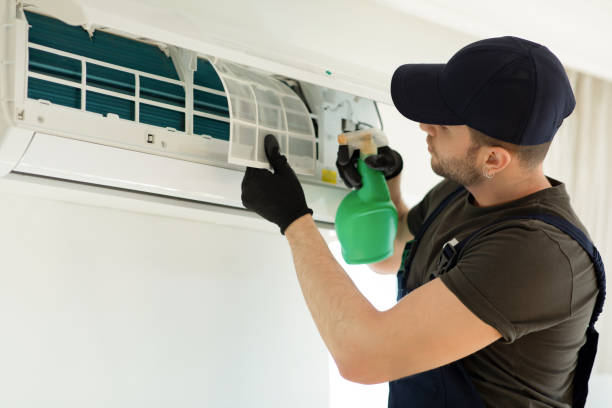 man spray cleaning an aircon filter