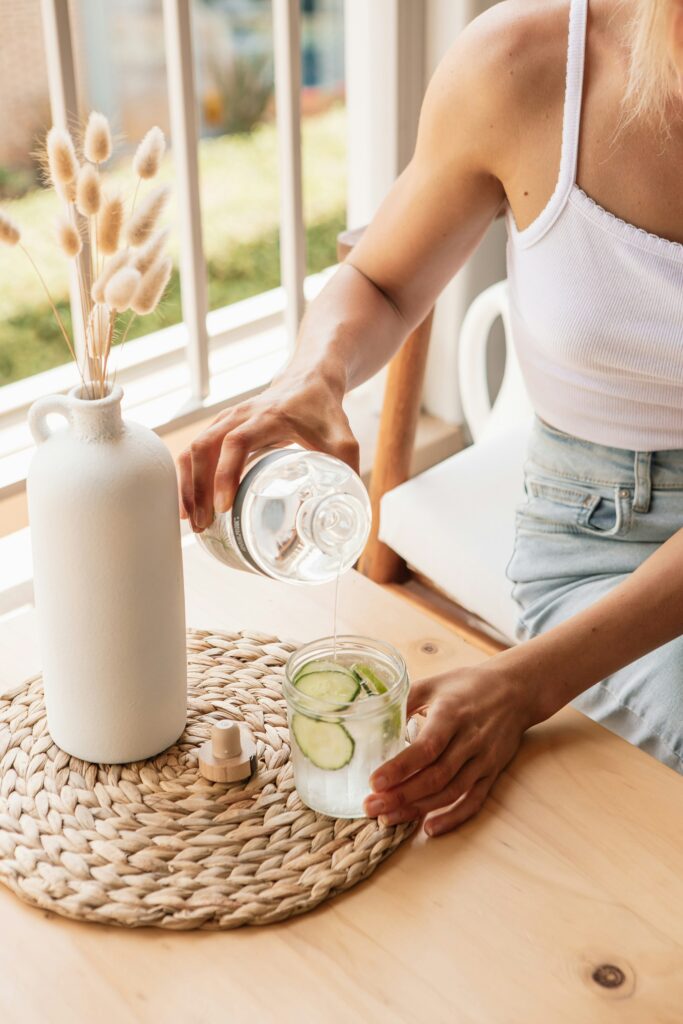 woman pouring a glass of cucumber water to rehydrate herself 