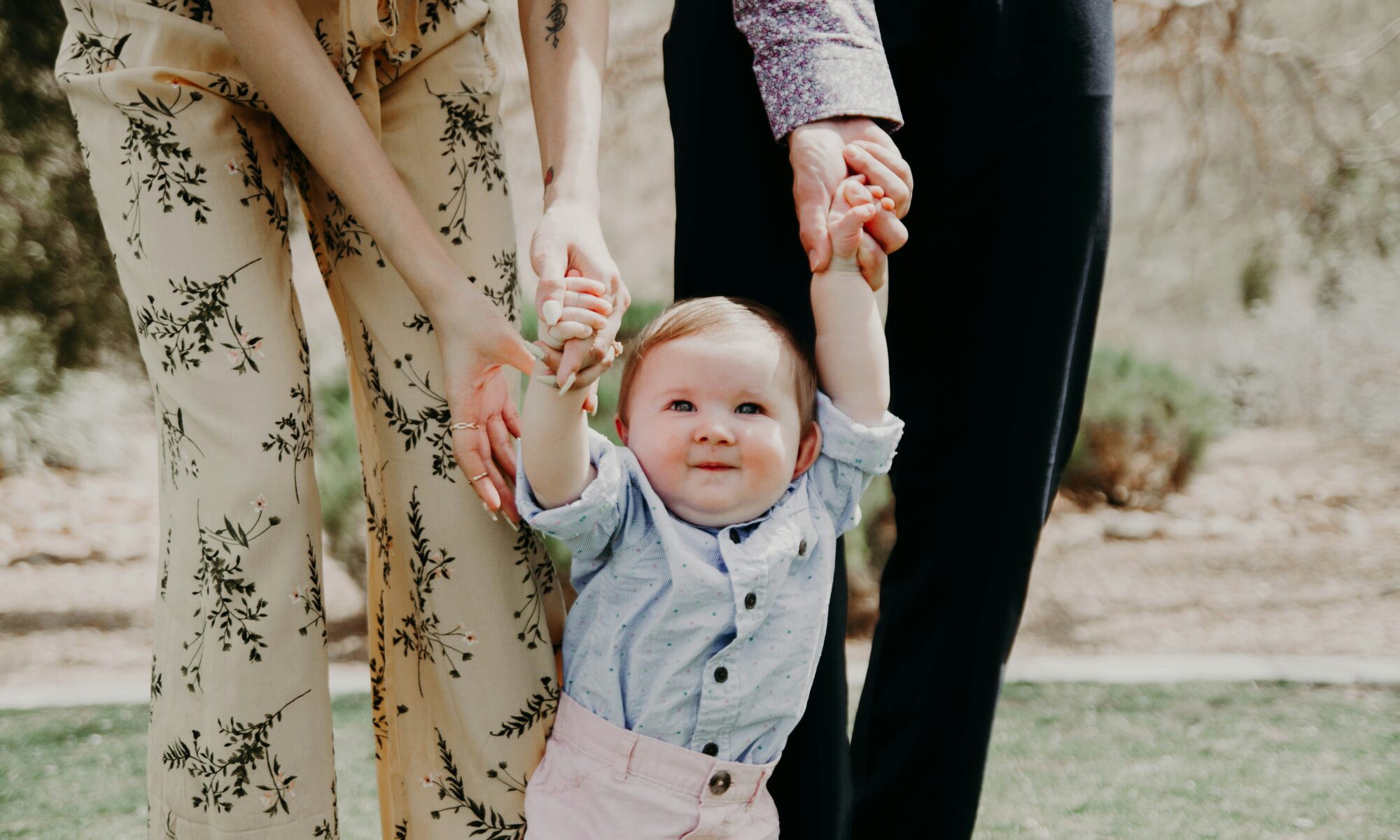 adults assisting a baby to stand