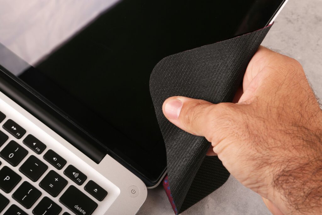 using a microfiber cloth to wipe a laptop screen