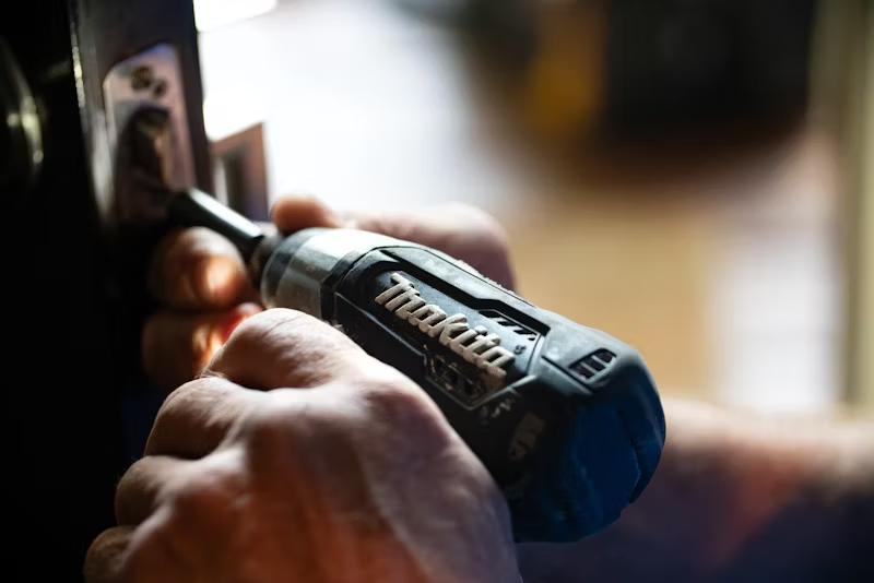 image of a handyman working on a door hinge