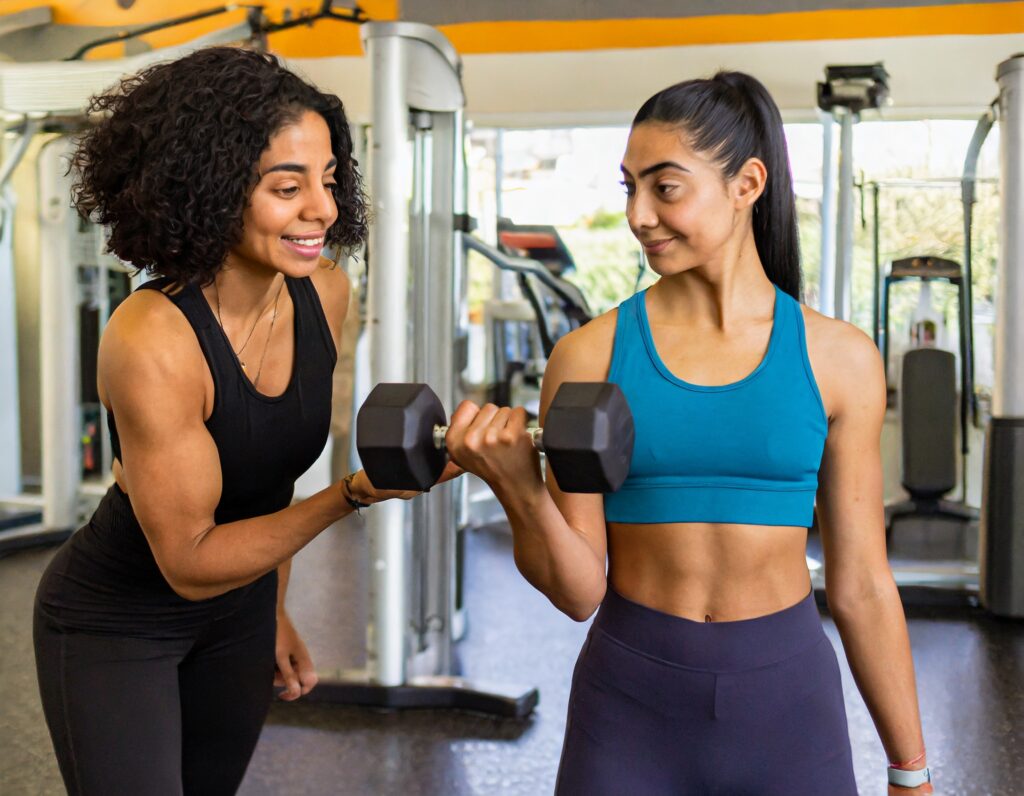female personal trainer teaching dumbbell curls