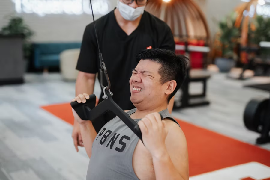gym goer doing a work out with the assistance of a personal trainer