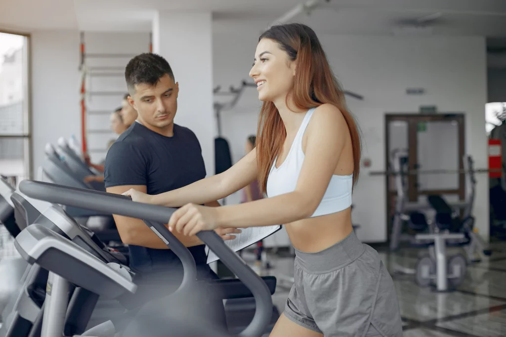 personal trainer guiding girl on treadmill